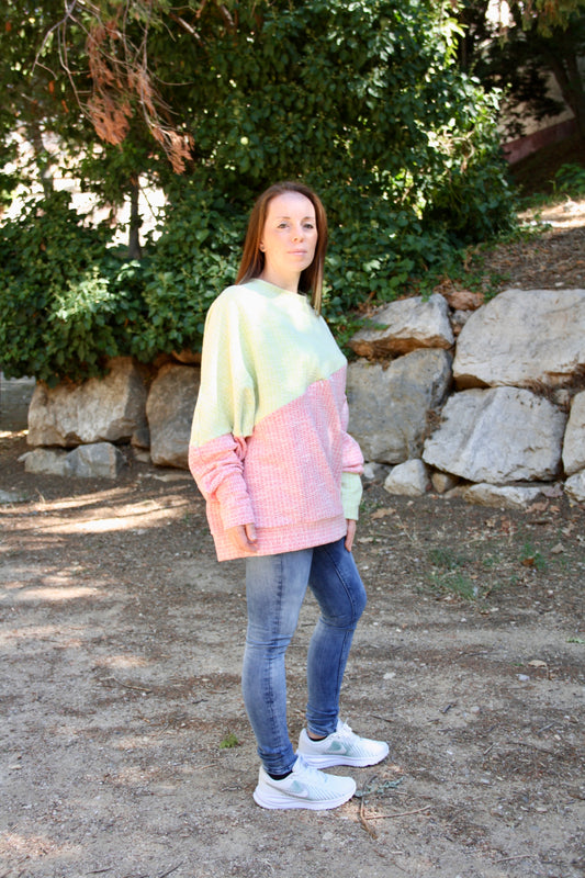 Jersey de lactancia bicolor en punto texturizado verde menta y rosa, con corte holgado y diseño asimétrico.