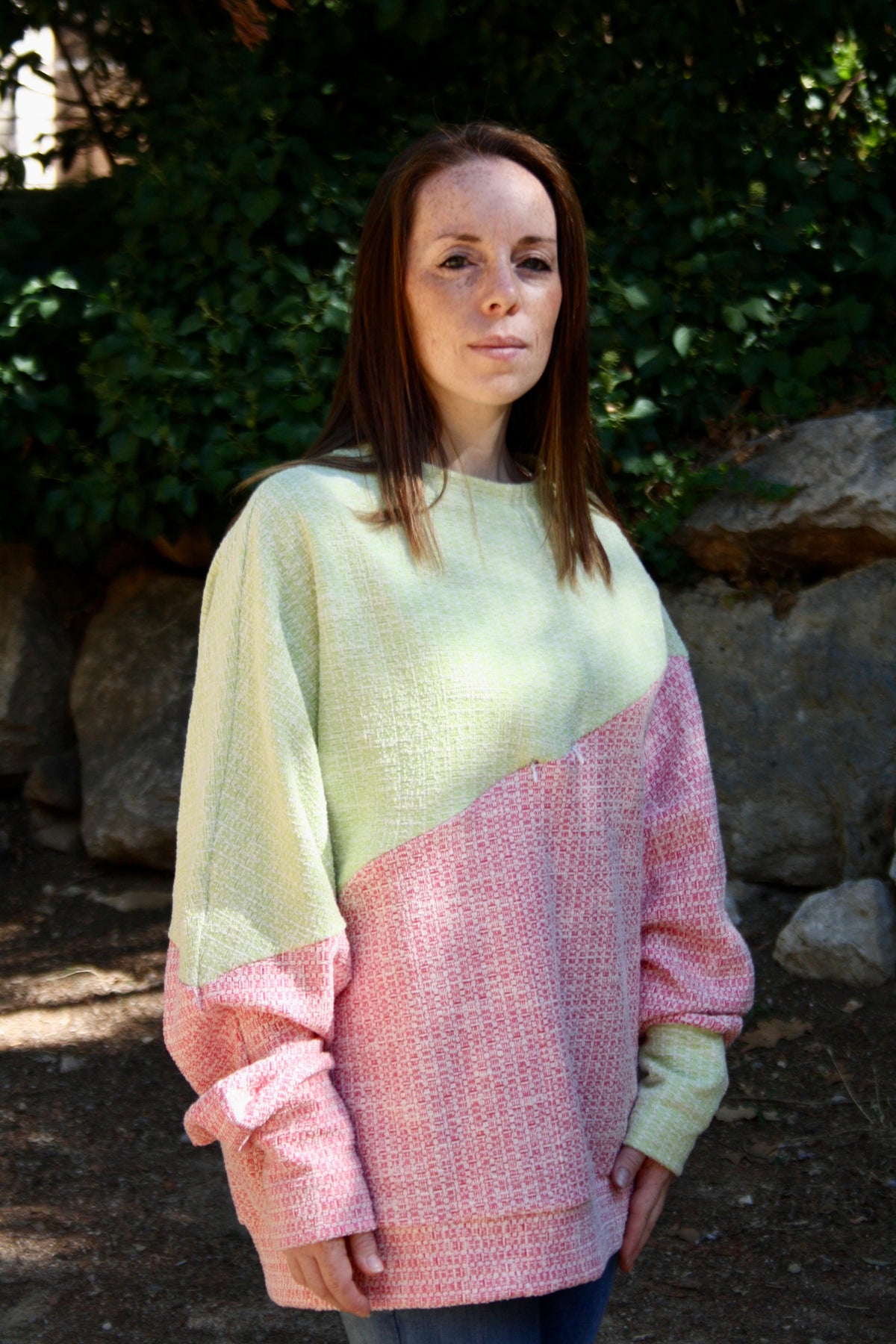 Jersey de lactancia bicolor en punto texturizado verde menta y rosa, con corte holgado y diseño asimétrico.